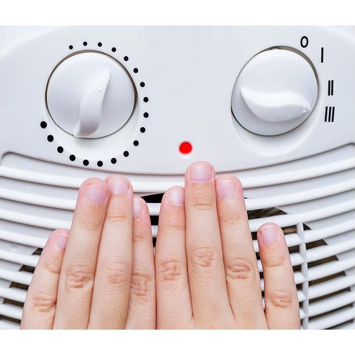 A closeup of hands being warmed by a space heater